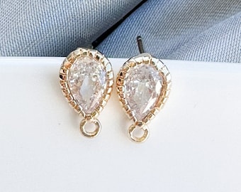 May include: A pair of gold teardrop-shaped earrings with clear crystal stones.