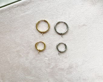 May include: Four hoop earrings, two gold and two silver, on a white background. The earrings are different sizes.