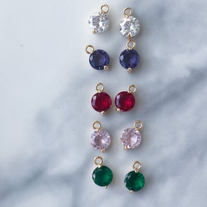 Puede incluir: Surtido de 10 colgantes redondos de amuleto de tono dorado con piedras de imitaci&oacute;n de diferentes colores. Los amuletos tienen un bucle en la parte superior para sujetarlos a joyas.