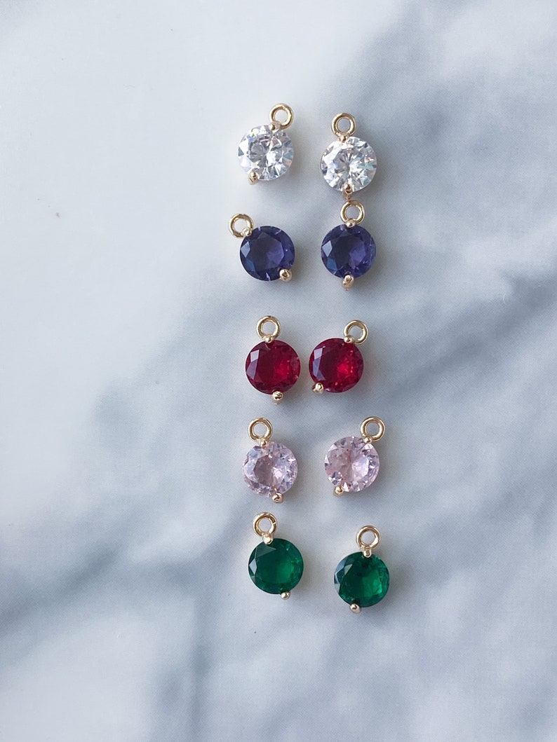 Puede incluir: Surtido de 10 colgantes redondos de amuleto de tono dorado con piedras de imitaci&oacute;n de diferentes colores. Los amuletos tienen un bucle en la parte superior para sujetarlos a joyas.