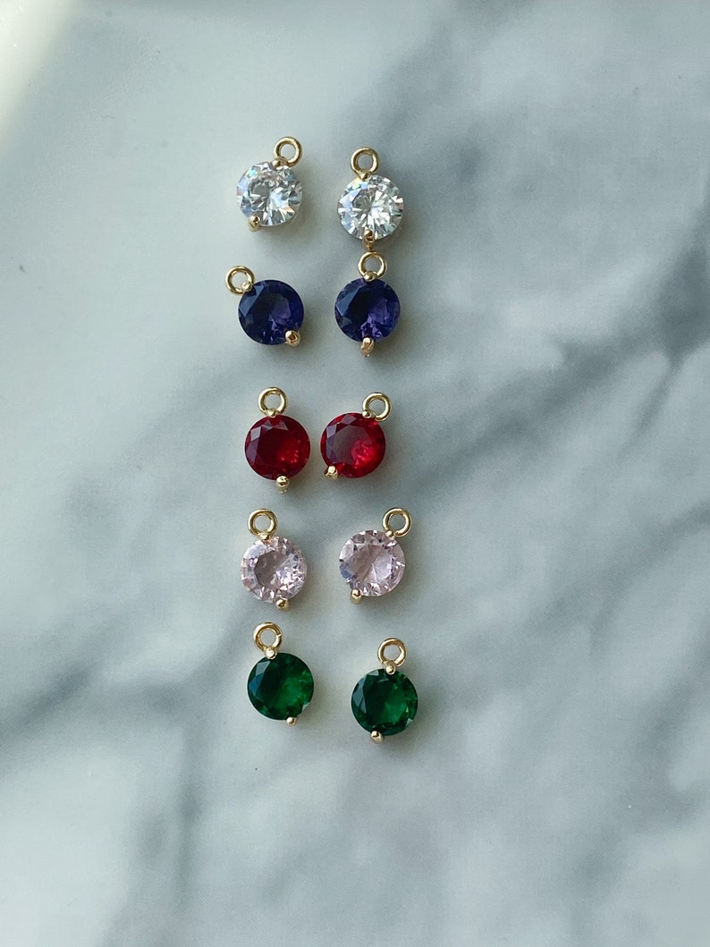 Puede incluir: Un conjunto de 10 abalorios redondos de piedras preciosas de color dorado con un bucle para sujetarlos a joyas. Los abalorios son de varios colores, incluyendo transparente, azul, rojo, rosa y verde.