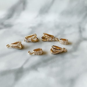 May include: Five gold-tone pendant clasps with clear crystal accents. Each clasp has a double-loop design.