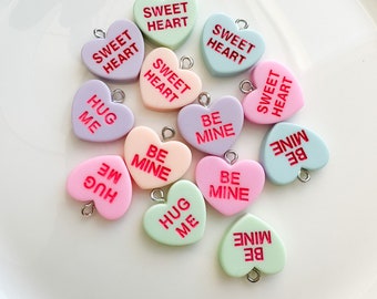 May include: Assortment of pastel-colored heart-shaped charms with various Valentine's Day messages, including "Sweet Heart", "Hug Me", and "Be Mine".