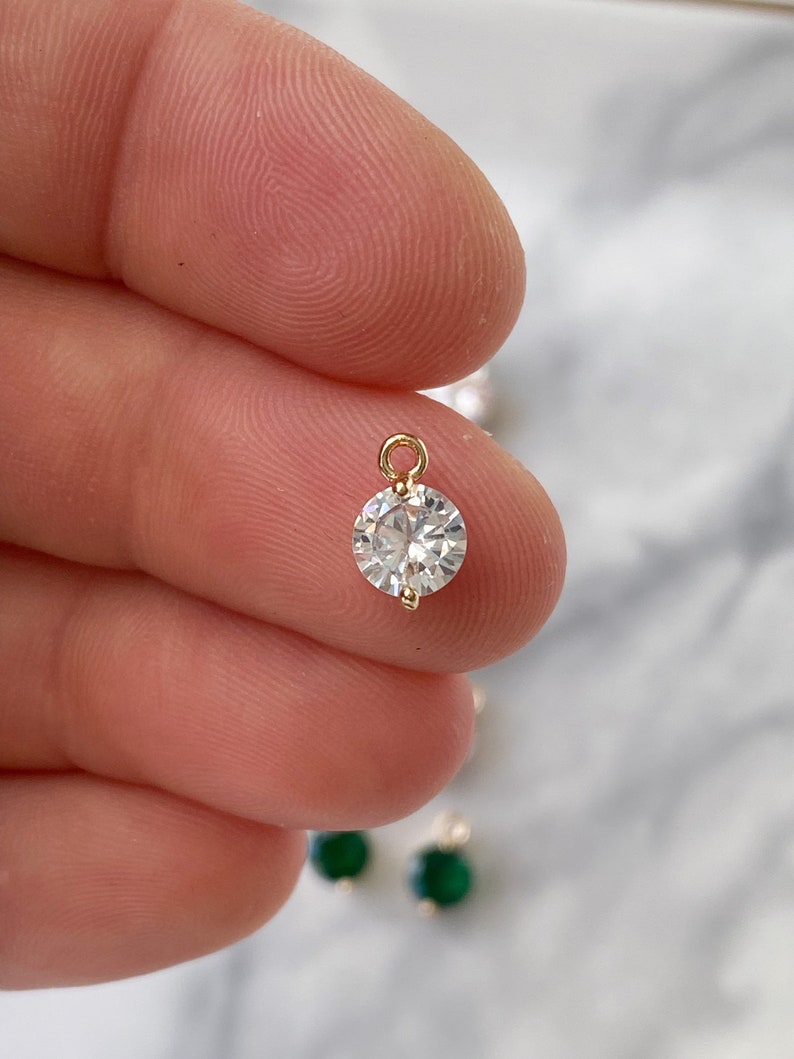 Puede incluir: Un colgante dorado con una piedra redonda de cristal transparente.