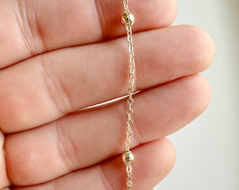May include: A gold chain necklace with small round beads.