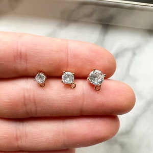May include: Three gold-toned round pendant charms with clear cubic zirconia stones. The charms have a loop on the bottom for attaching to jewelry.