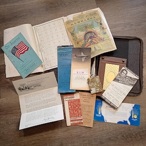 May include: A collection of vintage ephemera, including a calendar, pamphlets, and booklets. Items include a booklet titled "Our America" with an American flag, a map of Nebraska, and a "Where to Fish" guide.