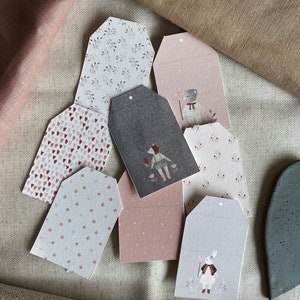 Puede incluir: Un conjunto de ocho etiquetas para regalos con varios patrones e ilustraciones. Las etiquetas est&aacute;n hechas de papel y tienen un agujero perforado en la parte superior para una cuerda o cinta. Los patrones incluyen corazones, estrellas y dise&ntilde;os florales. Las ilustraciones presentan animales y otros personajes caprichosos.