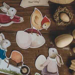K&ouml;nnte beinhalten: Ein Set aus Osterschnitten aus Papier mit einem K&uuml;ken, Hasen und Eiern. Die Ausschnitte befinden sich auf einer Holzoberfl&auml;che mit braunem Hintergrund. Der Text "That Way!" befindet sich auf einem der Ausschnitte.