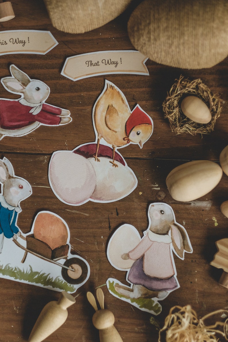 K&ouml;nnte beinhalten: Ein Set aus Osterschnitten aus Papier mit einem K&uuml;ken, Hasen und Eiern. Die Ausschnitte befinden sich auf einer Holzoberfl&auml;che mit braunem Hintergrund. Der Text "That Way!" befindet sich auf einem der Ausschnitte.
