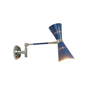 Può includere: Applique da parete blu e argento con un design moderno della metà del secolo. La lampada presenta un paralume a forma di cono con piccole aperture luminose, un braccio orientabile e un supporto a parete circolare. La lampada è in metallo e ha una finitura lucida.