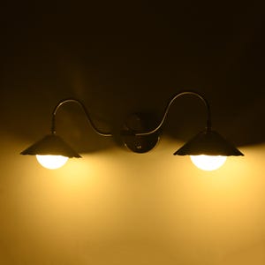 Double arm wall sconce featuring fluted silver shades and warm ambient lighting