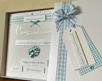 Può includere: Biglietto di annuncio nascita con nastro e fiocco a quadretti blu e bianchi. Il biglietto dice "Congratulazioni" e include il nome, la data di nascita e il peso del bambino. Il biglietto è decorato con stelle blu e paillettes.