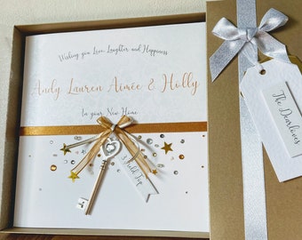 May include: A white card with gold and silver embellishments, a key, and the text "Wishing you Love, Laughter and Happiness Andy Lauren Aimee & Holly In your New Home 3 Full Top The Dearloves".