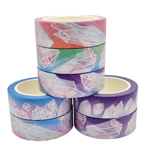 Peut inclure: Quatre rouleaux de ruban adhésif washi avec un motif de cristal. Le ruban est dans des tons de rose, vert, violet et bleu.