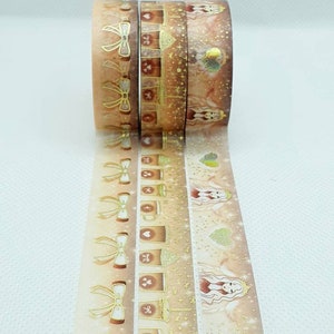 May include: Three rolls of washi tape with a fall theme. The tape features gold foil accents, illustrations of coffee cups, bows, and a woman with wings. The text "Pumpkin Spice" is at the top of the image.