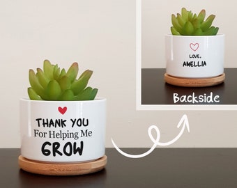 May include: White ceramic planter with a succulent plant and a red heart. The planter has the text "Thank You For Helping Me GROW" on the front. The back of the planter has the text "Love, Amelia".