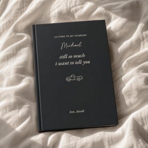 May include: A black hardback journal with white text that reads LETTERS TO MY HUSBAND, Michael, still so much i want to tell you, and love, Sarah. A small white line drawing of a pickup truck is centred between the text on the front cover.