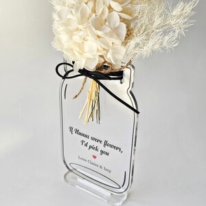 May include: A clear acrylic vase shaped like a mason jar with a black ribbon and dried white flowers. The vase has a white label with the text "If Nanas were flowers, I'd pick you" and a red heart. The label also includes the text "Love Claire & Issy".