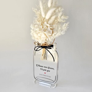May include: White dried flowers in a clear acrylic mason jar with a black ribbon and the text "If humans were flowers, I'd pick you Love Claire & Issy"