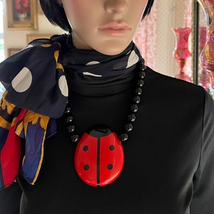 May include: A black and red ladybug pendant necklace with black beads. The pendant is large and has a glossy finish.