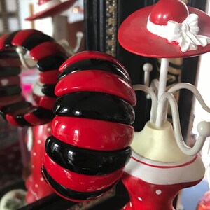 May include: A red and black striped plastic bangle bracelet. The bracelet is made of multiple stacked rings of red and black plastic.