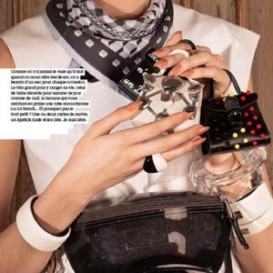 May include: A fashion-forward image featuring a black and white patterned scarf, a clear fanny pack, and several small, decorative handbags. One handbag is black with red and yellow accents. The image also includes text in French.