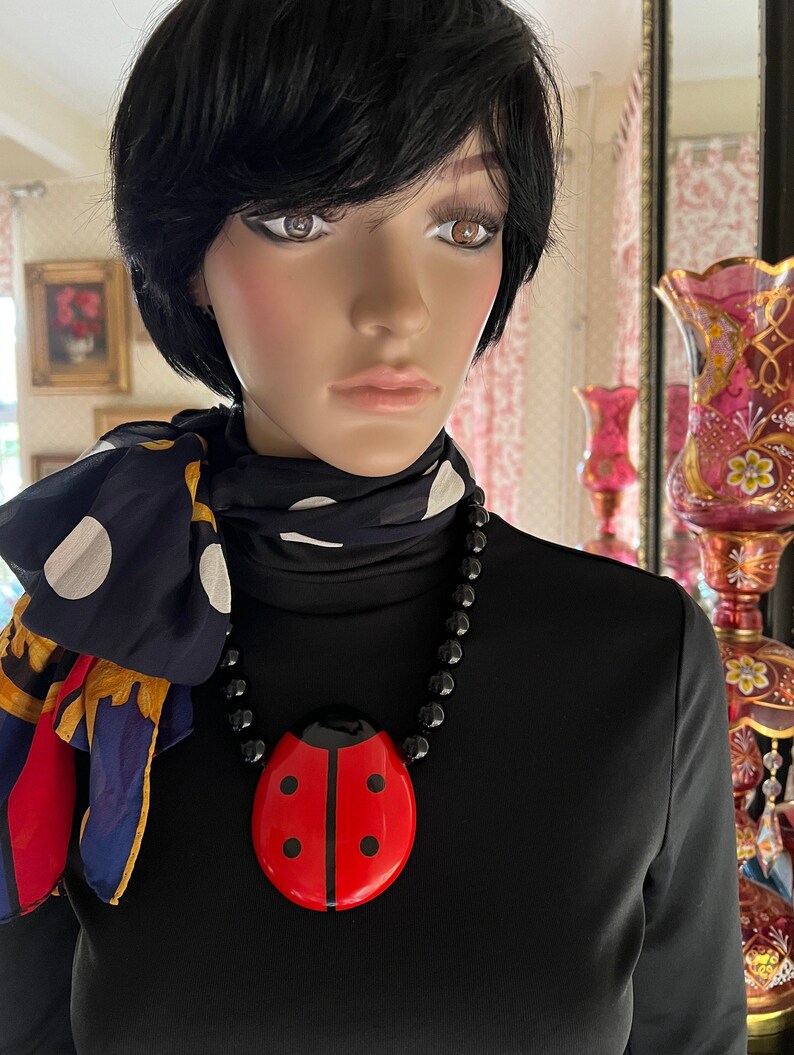 May include: A black and red ladybug pendant necklace with black beads. The pendant is large and has a glossy finish.