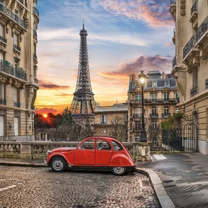 May include: A bright red vintage Citro&euml;n 2CV car parked on a cobblestone street in Paris. The Eiffel Tower is visible in the background under a sunset sky, framed by traditional stone apartment buildings with balconies and street lamps.