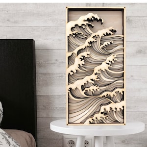 May include: A wooden wall art piece depicting a layered wave design. The wave is made of multiple layers of wood, creating a 3D effect. The wood is a light brown colour.