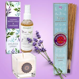Può includere: Una collezione di prodotti per aromaterapia, tra cui uno spray smudge, uno spray smudge senza fumo, una candela e bastoncini di incenso. I prodotti sono alla lavanda e salvia bianca, con un rametto di lavanda. La confezione include testo come "Yoga natural incense" e "Prana Lavender".