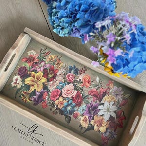 May include: A rectangular wooden serving tray with cutout handles, featuring a vibrant floral print on the base with lilies, roses, and assorted blossoms in shades of red, yellow, purple, and white. The text Leah Kendrick Design is printed in black.