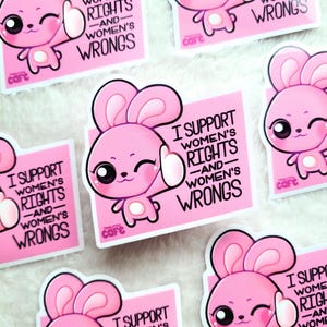 May include: Pink stickers featuring a cartoon bunny giving a thumbs up. The stickers have the text "I SUPPORT WOMEN'S RIGHTS -AND- WOMEN'S WRONGS". The stickers are from the "Twittle Cafe" brand.