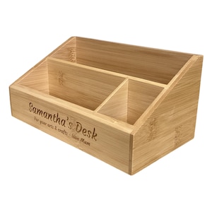 Op de afbeelding: Een lichtgekleurde bamboe bureau-organizer met meerdere compartimenten. De organizer heeft de tekst "Samantha's Desk" gegraveerd op de voorkant, samen met de zin "For your arts & crafts - love Mum". De organizer is ontworpen om bureau-artikelen in op te bergen.