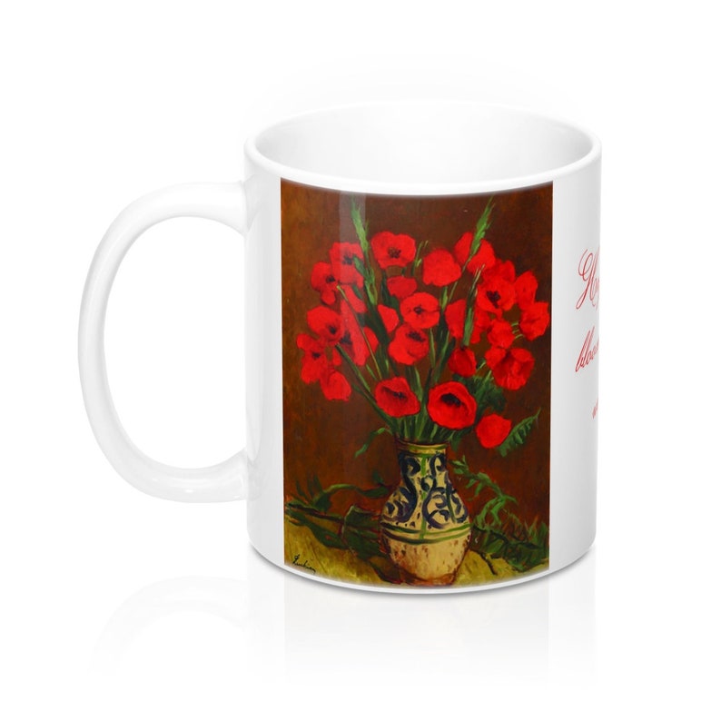 May include: White ceramic mug featuring a painting of red poppies in a decorative vase. The vase has a cream base with blue and green accents. The painting is set against a brown background. The mug has a white handle and the text "Red poppies blooming" in red.