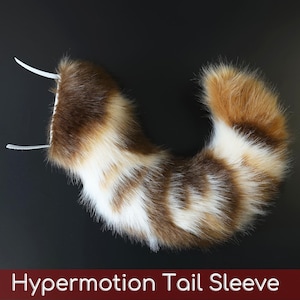 May include: A faux fur tail sleeve featuring a multi-colored pattern of brown, white, and orange fibers. The curved, plush accessory includes two white elastic loops at the top for attachment. The text Hypermotion Tail Sleeve is visible.
