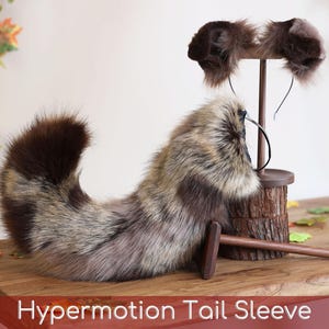 May include: A faux fur animal tail with brown, gray, and black variegated coloring, paired with a matching set of animal ears on a thin headband. The text "Hypermotion Tail Sleeve" is displayed at the bottom of the image.