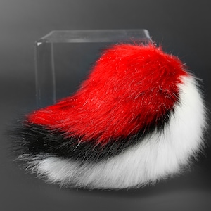 K&ouml;nnte beinhalten: Ein flauschiger, roter, schwarzer und wei&szlig;er Kunstfellschwanz mit einem langen, flie&szlig;enden Design.
