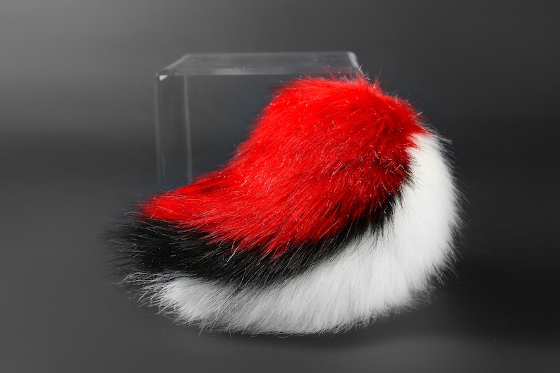 K&ouml;nnte beinhalten: Ein flauschiger, roter, schwarzer und wei&szlig;er Kunstfellschwanz mit einem langen, flie&szlig;enden Design.