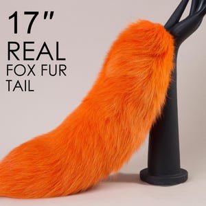 May include: A 17 inch long orange real fox fur tail. The tail is attached to a black stand.