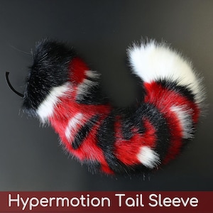 May include: A faux fur tail sleeve featuring a vibrant pattern of black, red, and white stripes with a solid white tip. The accessory includes a black elastic attachment loop at the base and is labeled with the text Hypermotion Tail Sleeve.