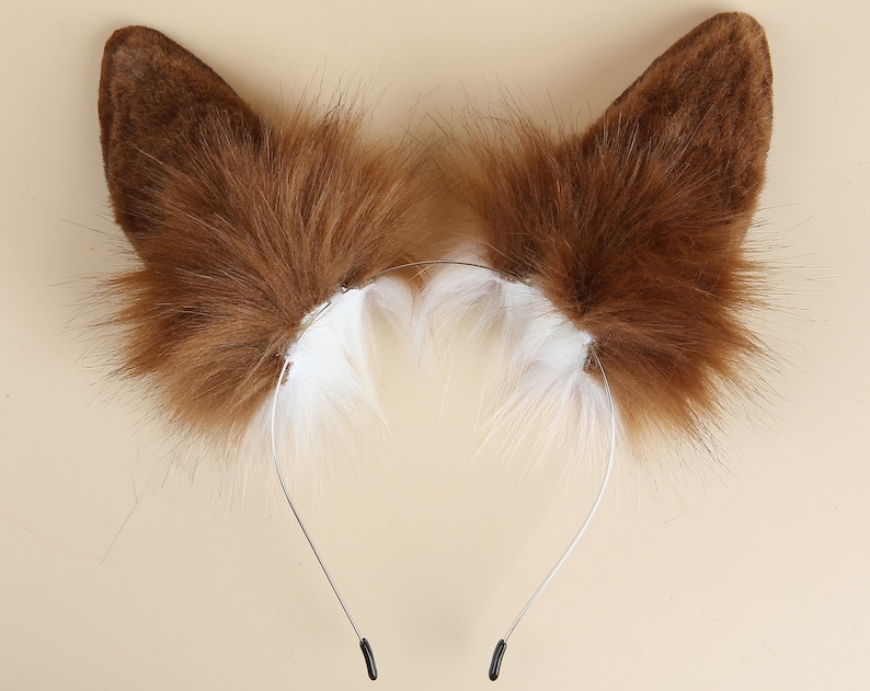 May include: Brown faux fur cat ears headband with a white fur trim. The headband is made of a thin metal wire and has black plastic ends.