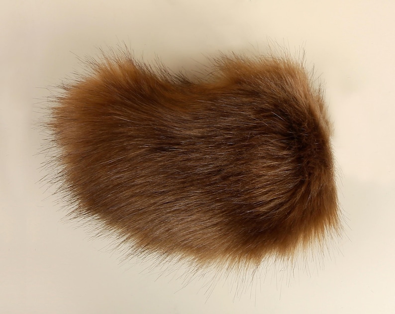 May include: A brown faux fur tail with long, soft fibers. The tail is fluffy and appears to be made of high-quality material.