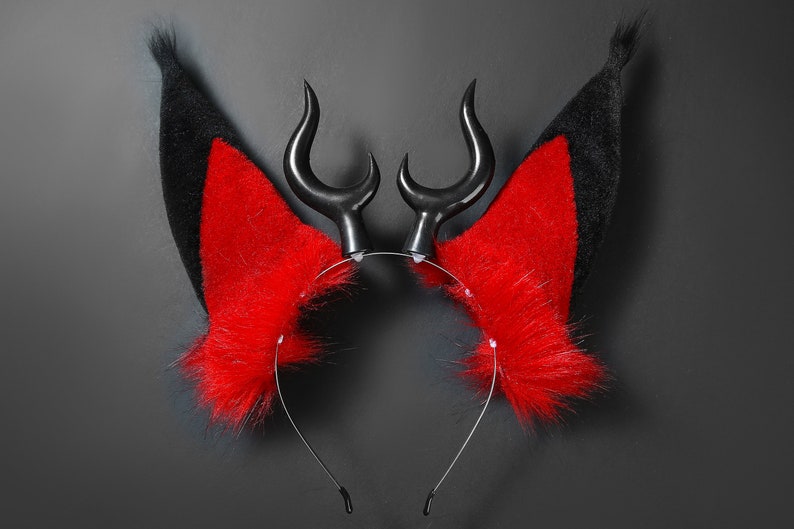 K&ouml;nnte beinhalten: Ein schwarzes Stirnband mit roten und schwarzen Fell-Ohren und schwarzen H&ouml;rnern. Das Stirnband ist f&uuml;r Cosplay oder Kost&uuml;mverwendung.