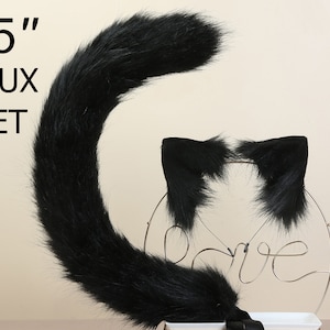 May include: A black faux fur tail and a pair of black faux fur cat ears. The tail is 25 inches long. The set is displayed on a white stand with a silver wire love sign.