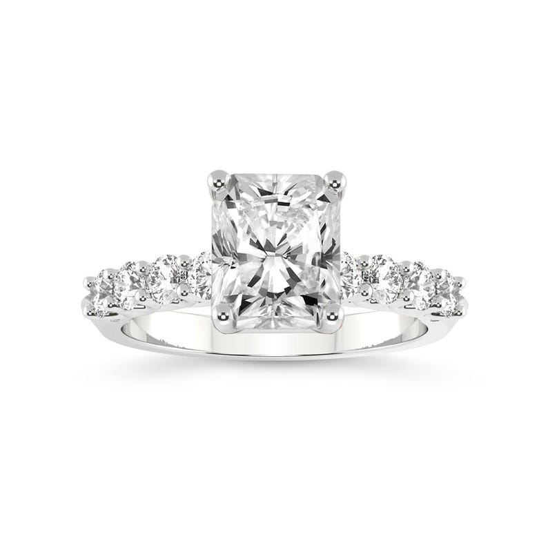 K&ouml;nnte beinhalten: Ein quadratischer Diamantring mit Pav&eacute;-Fassung. Der Ring hat eine silberne Band und einen gro&szlig;en, klaren Mittel-Stein.