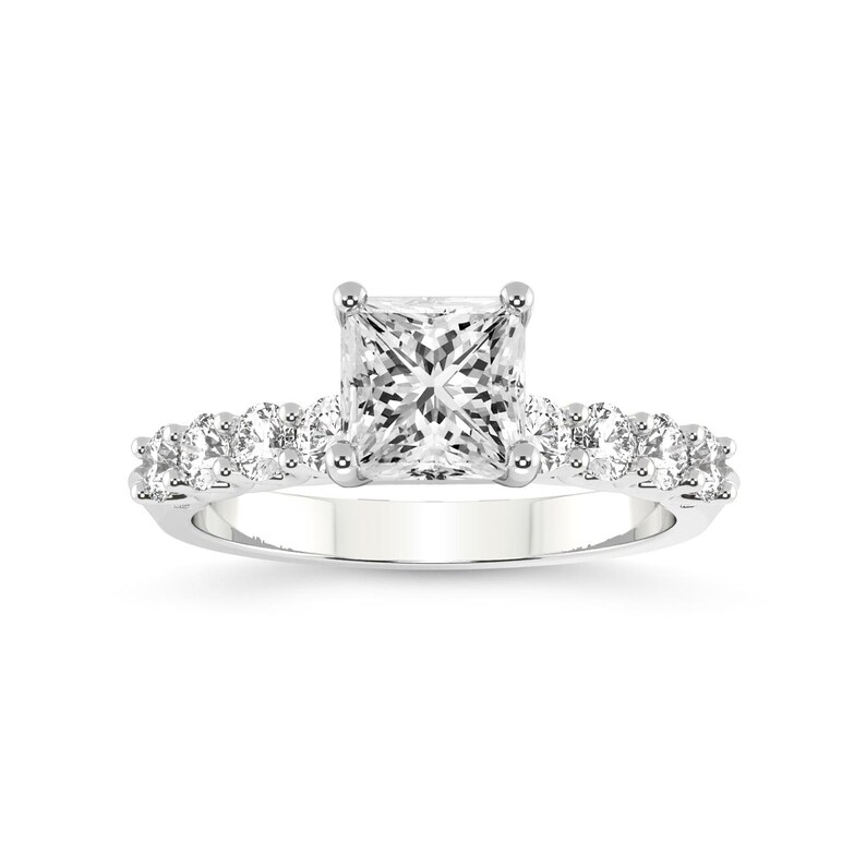 K&ouml;nnte beinhalten: Ein silberner Verlobungsring mit einem quadratischen Diamanten in der Mitte und einer Reihe kleinerer Diamanten.