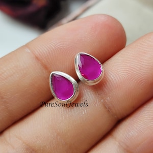 May include: A pair of sterling silver earrings with teardrop-shaped pink gemstones. The earrings are simple and elegant, perfect for everyday wear.