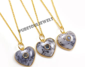 May include: Three gold-colored necklaces with heart-shaped pendants. Each pendant has a gold border, a light gray and black stone, and a small blue gemstone in the center. The necklaces are on a white background. The text "PURESOULJEWELS" is visible.