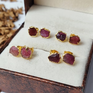 Peut inclure: Six paires de boucles d'oreilles plaquées or avec des pierres de rubis roses. Les boucles d'oreilles sont dans une petite boîte brune.